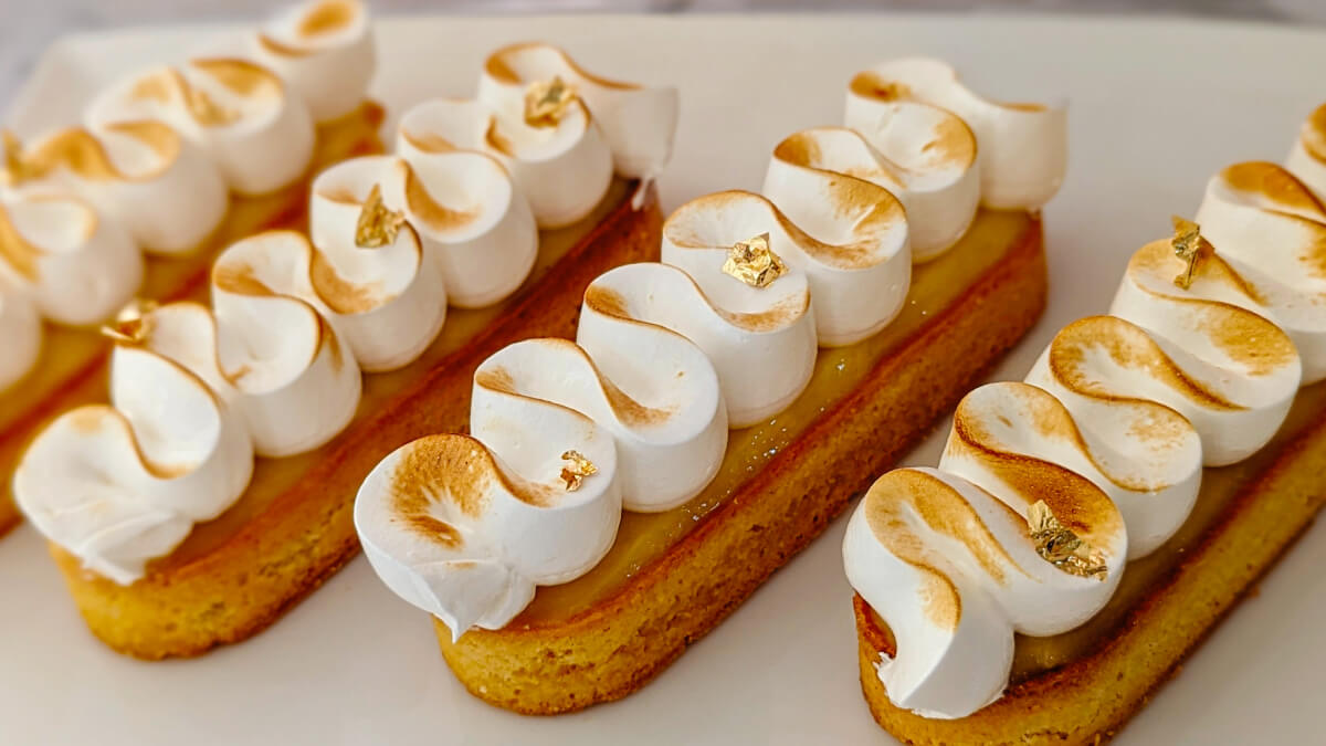 Des tartelettes citron meringuées sur une assiette blanche.