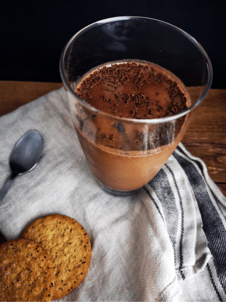 Un verre de smoothie chocolat sur un torchon avec deux cookies.