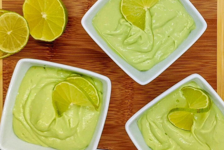 Des crèmes dessert citron vert dans des ramequins blancs, sur un fond en bois.