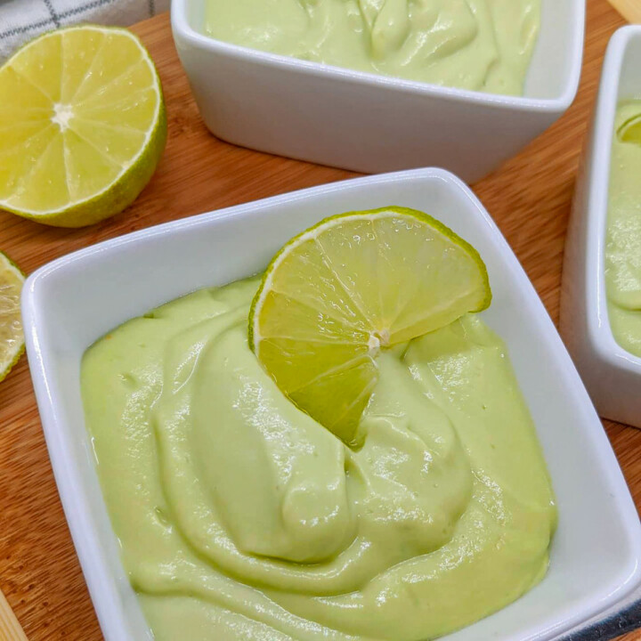 Des crèmes dessert citron vert dans des ramequins blancs, sur un fond en bois.