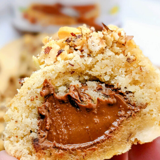 Une main tenant une boule de noisettes ouverte en deux, montrant un cœur Nutella.