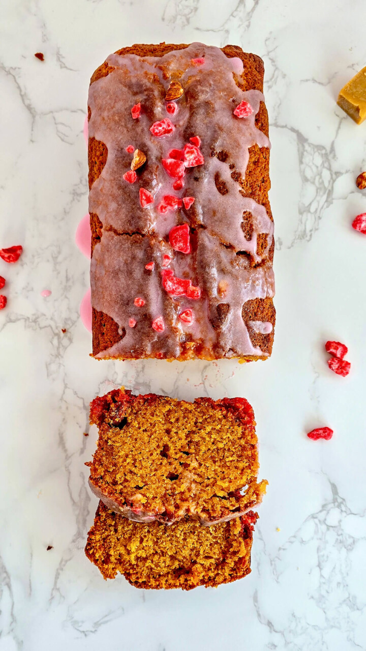 Un cake caramel et pralines roses très moelleux sur un fond marbré.