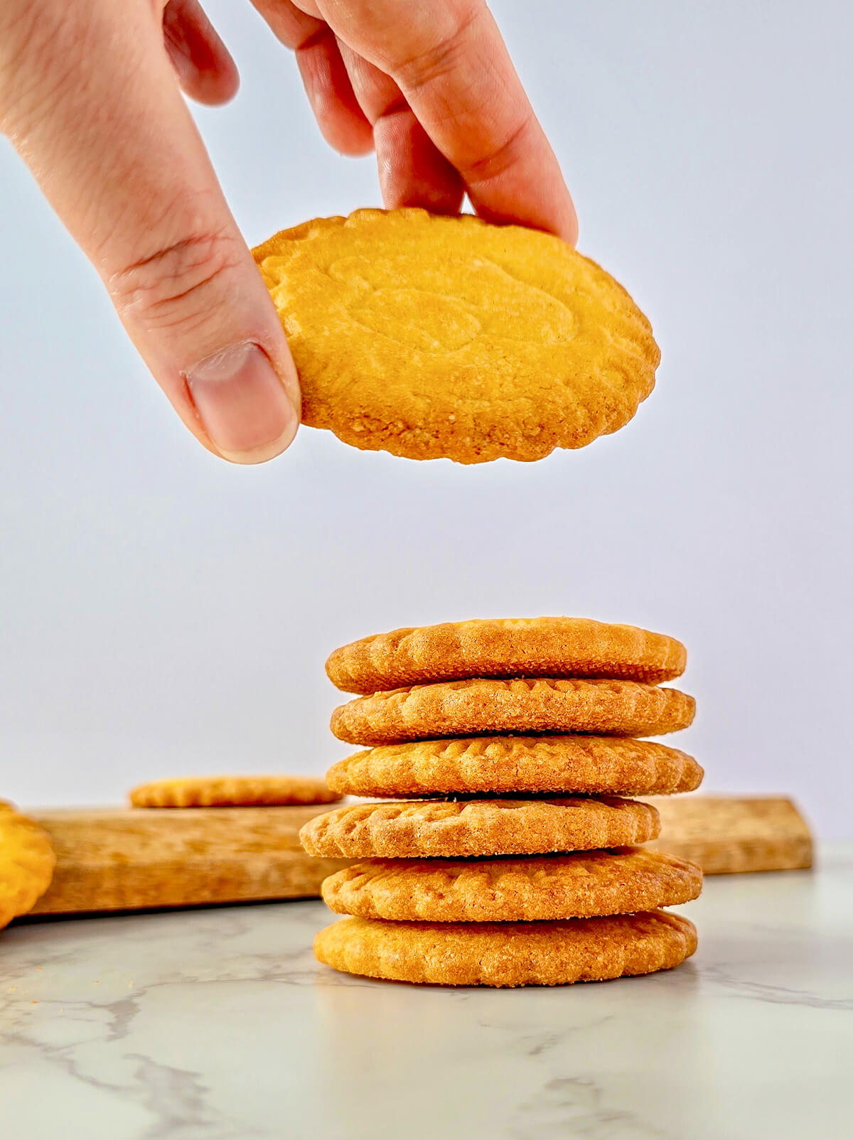 Pile de sablés bretons pur beurre faits maison, dorés et croustillants, présentés sur un plan de travail en marbre blanc.