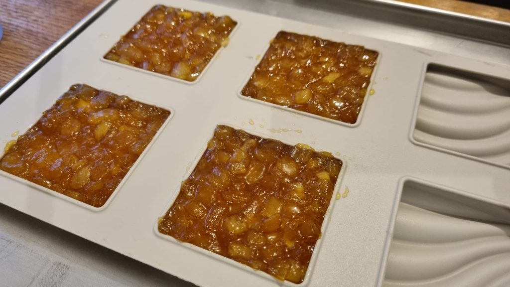 Des pommes caramélisées dans le moule en silicone pour faire des tartelettes tatin aux pommes.