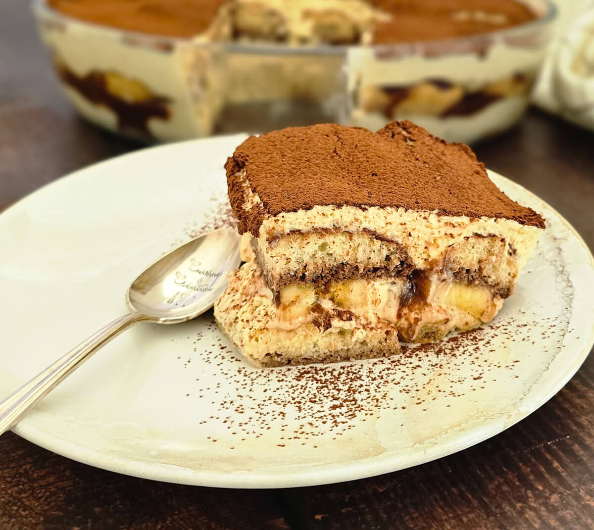 Une part de tiramisu Nutella banana dans une assiette blanche avec une cuillère.