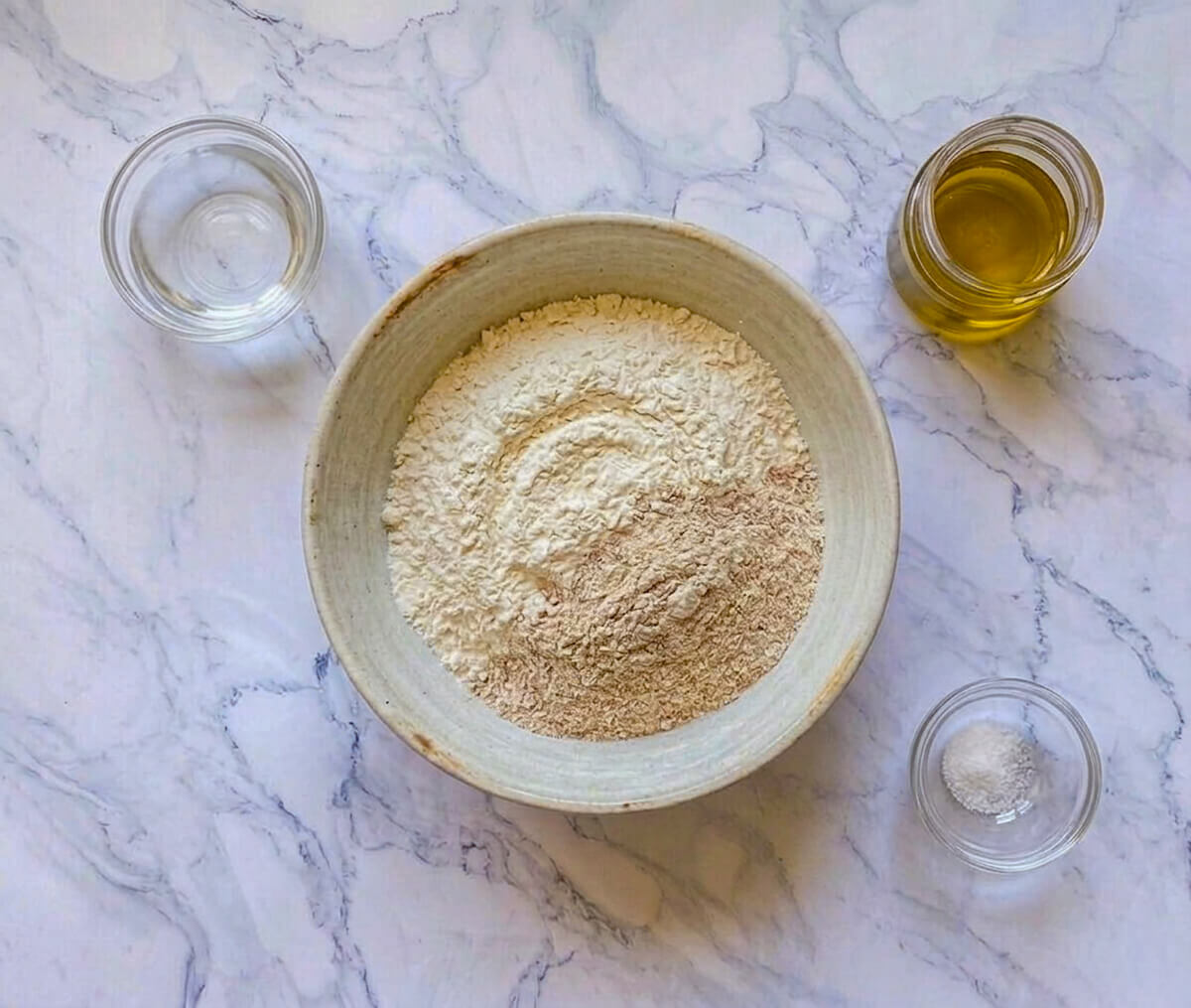 Des ingrédients pour une recette de petits pains minute, sur un fond blanc marbré.