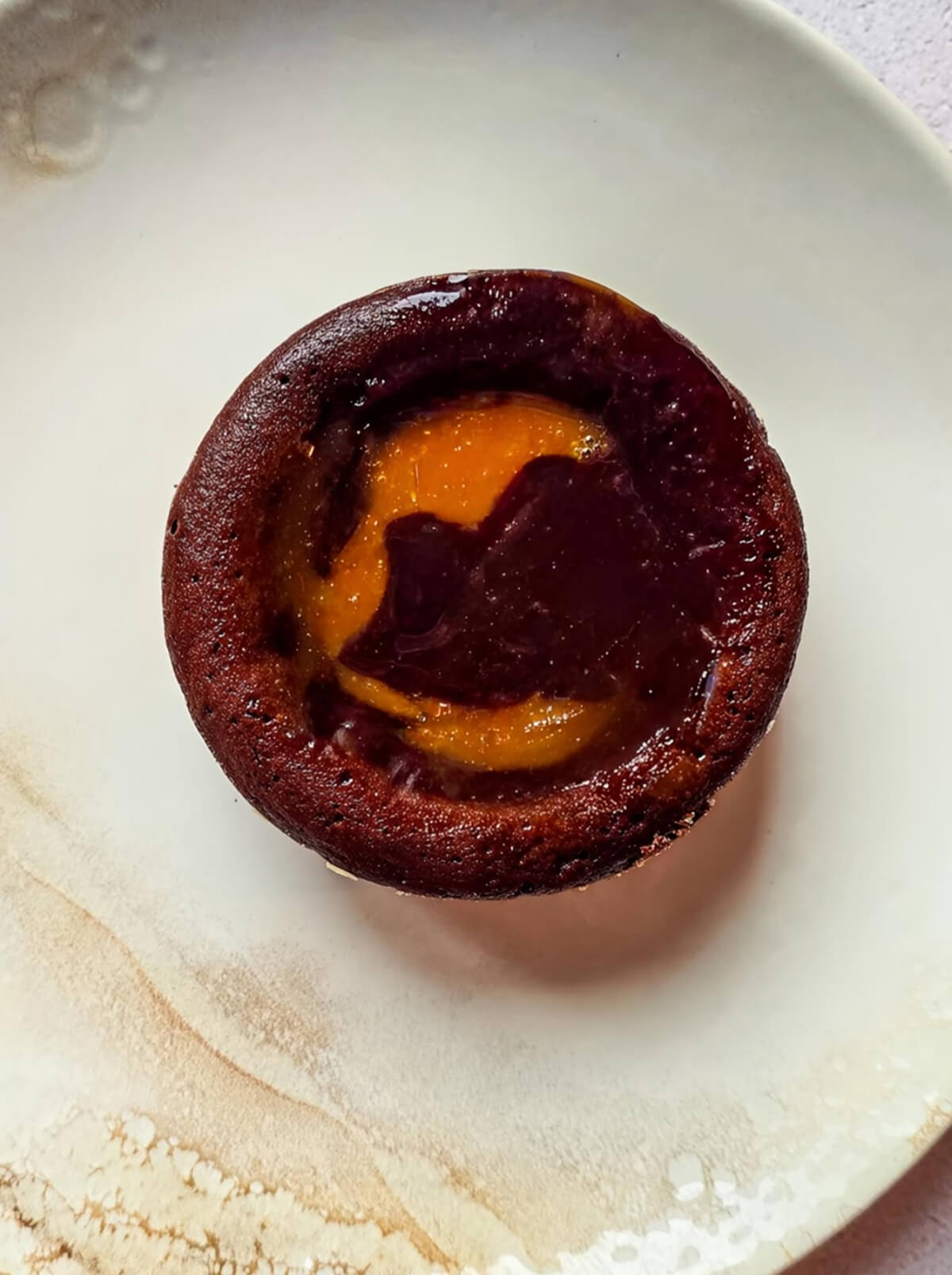 Un fondant au chocolat coeur caramel dans une assiette beige clair.
