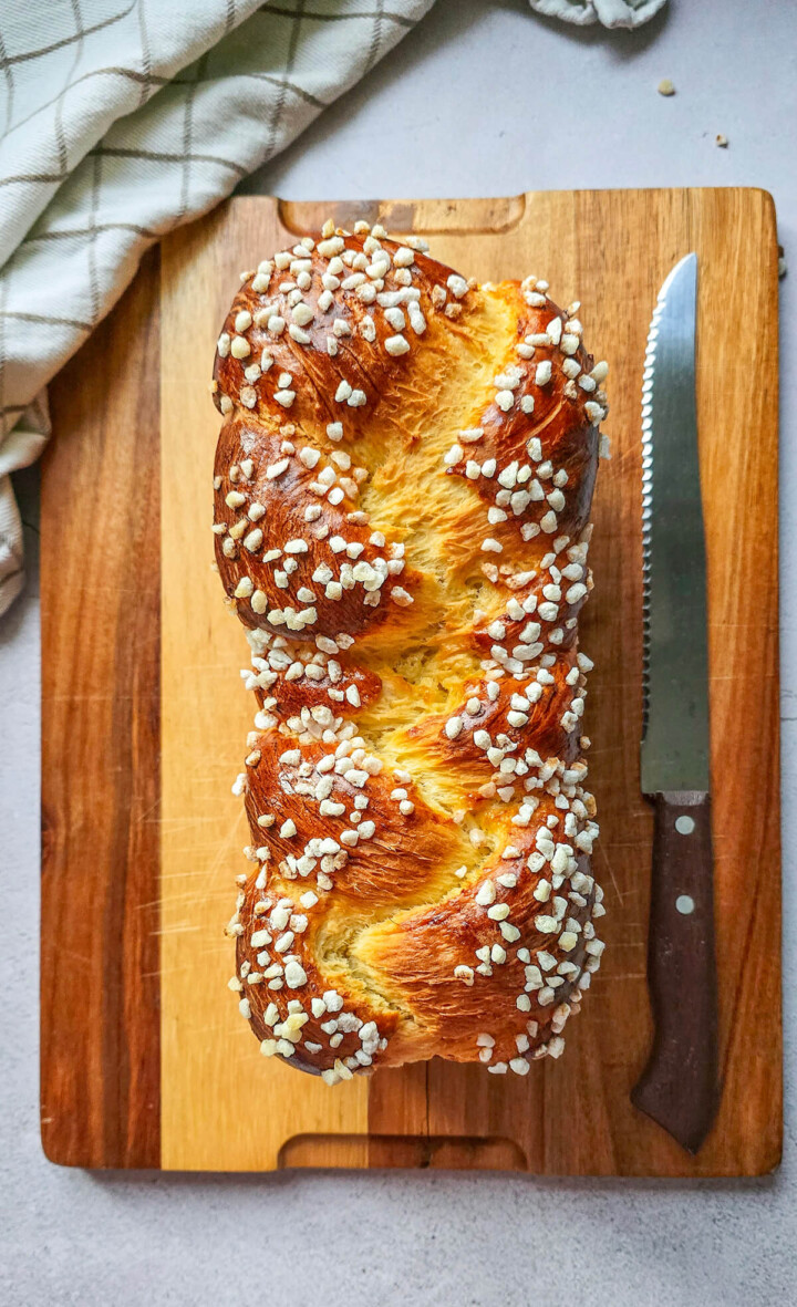 Une brioche tressée filante sur une planche de bois, couteau sur le côté.