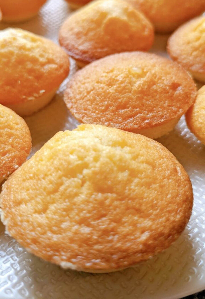 Des madeleines moelleuses au coeur fondant citron sur une assiette blanche.