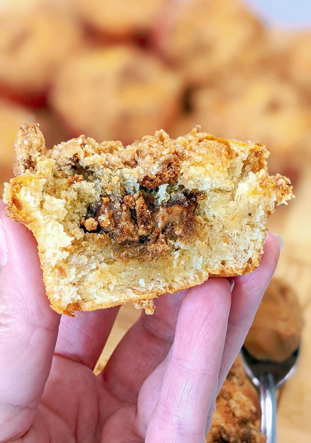Une main tenant un morceau de muffin au Spéculoos, coupé en deux, avec le coeur fondant Spéculoos.