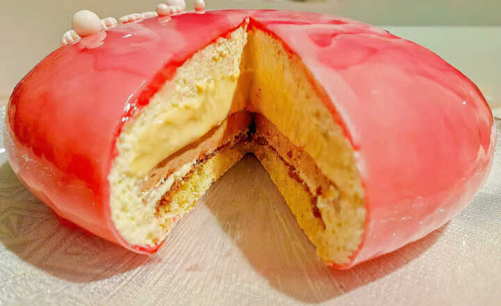 Entremets vanille caramel, coupé, recouvert d'un glaçage miroir rose dégradé à trois teintes.