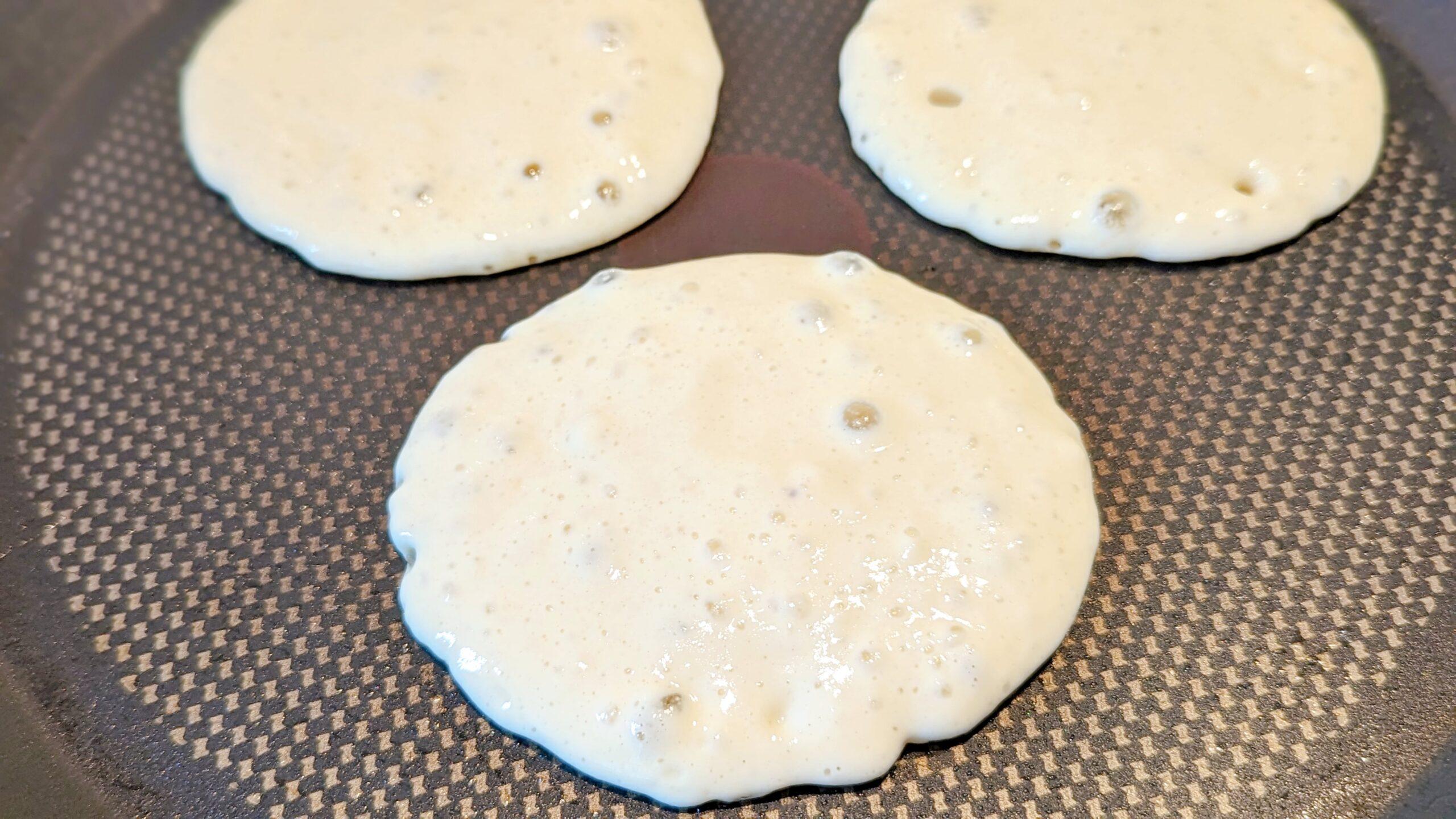 Des pancakes qui font des bulles dans une poele, pour une recette de pancakes fluffy au yaourt.