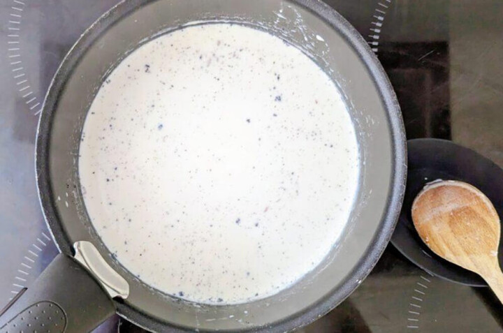 Cuisson d'une crème anglaise à la vanille dans une casserole avec une cuillère en bois.