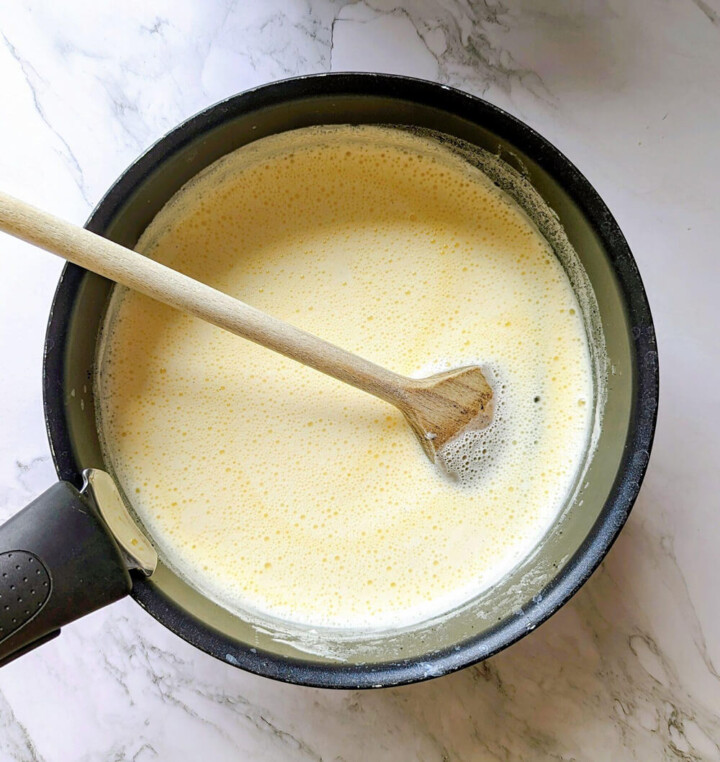 Verser le lait chaud sur le mélange jaunes d'œufs et sucre dans une casserole tout en remuant avec une cuillère en bois.