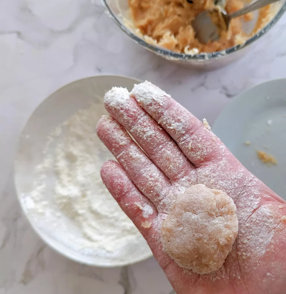 Une main tenant un morceau de poulet pour le faconner, pour en faire des nuggets de poulet.