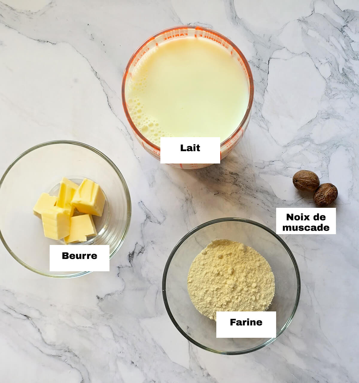 Des ingrédients pour faire une béchamel maison traditionnelle sur un fond blanc marbré.