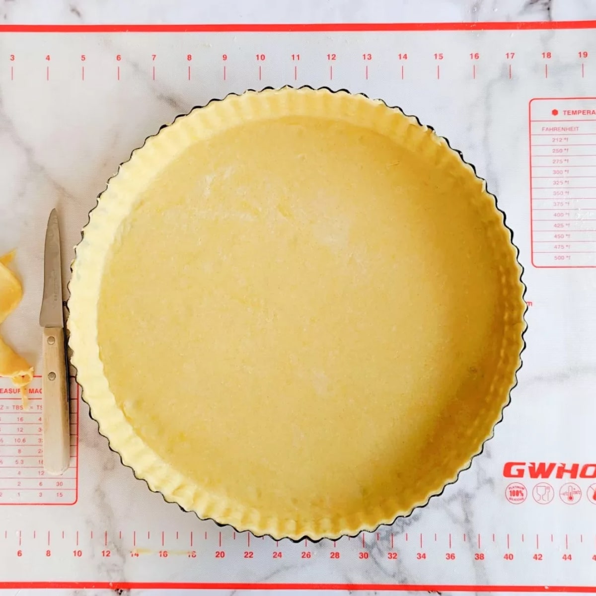 Une pâte brisée non cuite dans son moule à tarte.