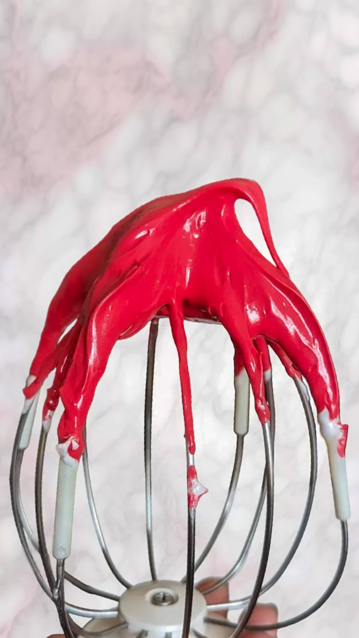 De la meringue de couleur framboise sur un fouet.