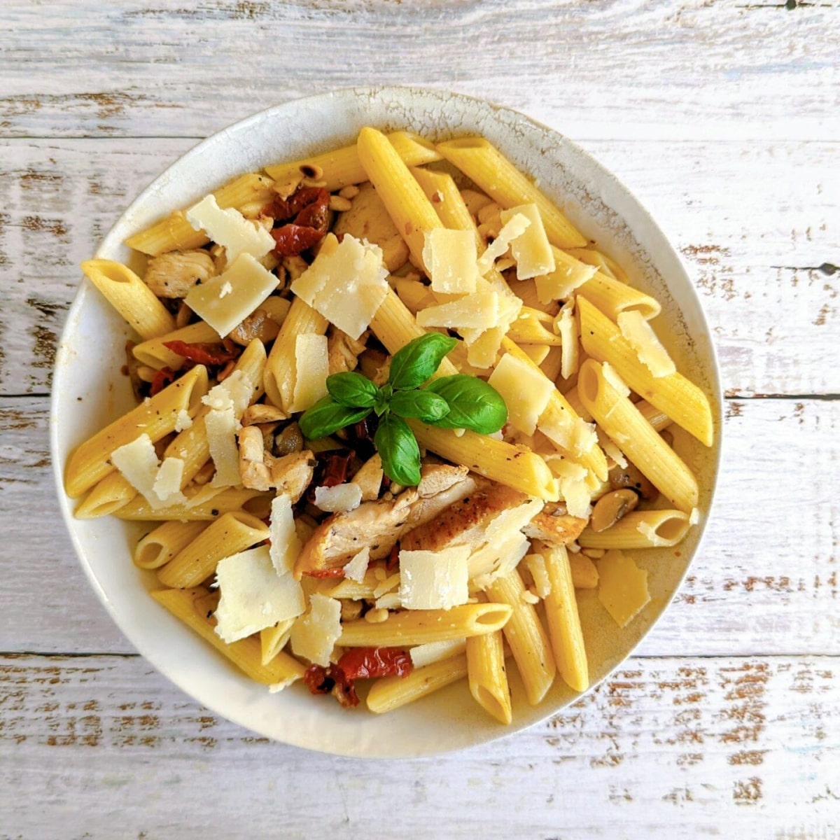 Une salade de pâtes froide dans un bol beige, sur un fond bois clair.