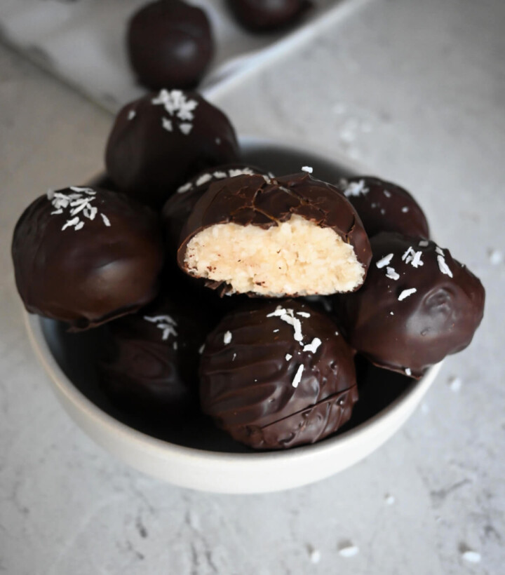Des rochers coco vegan dans un bol blanc, sur fond gris clair