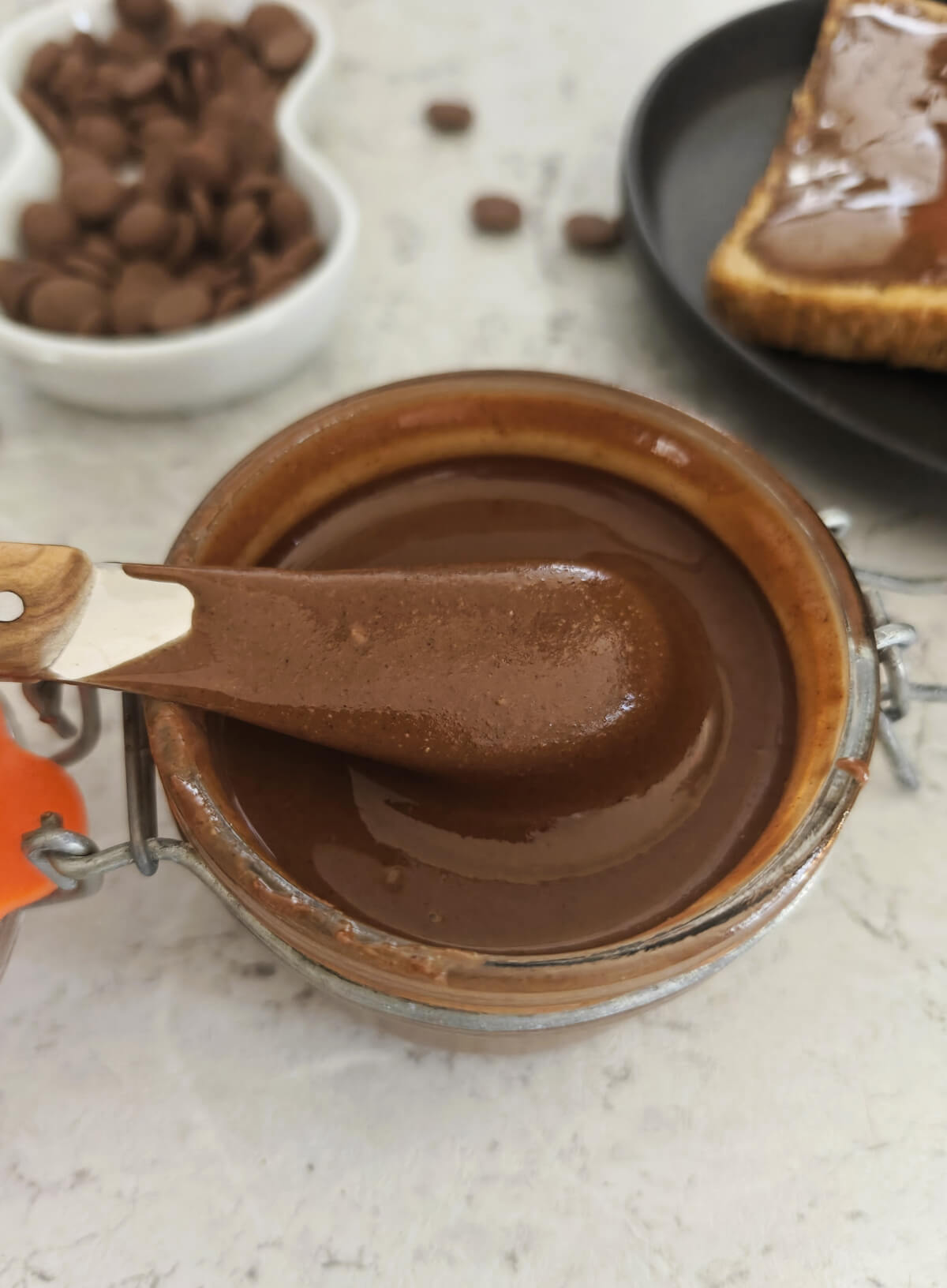 De la pâte à tartiner maison dans un pot en verre avec un couteau à beurre.