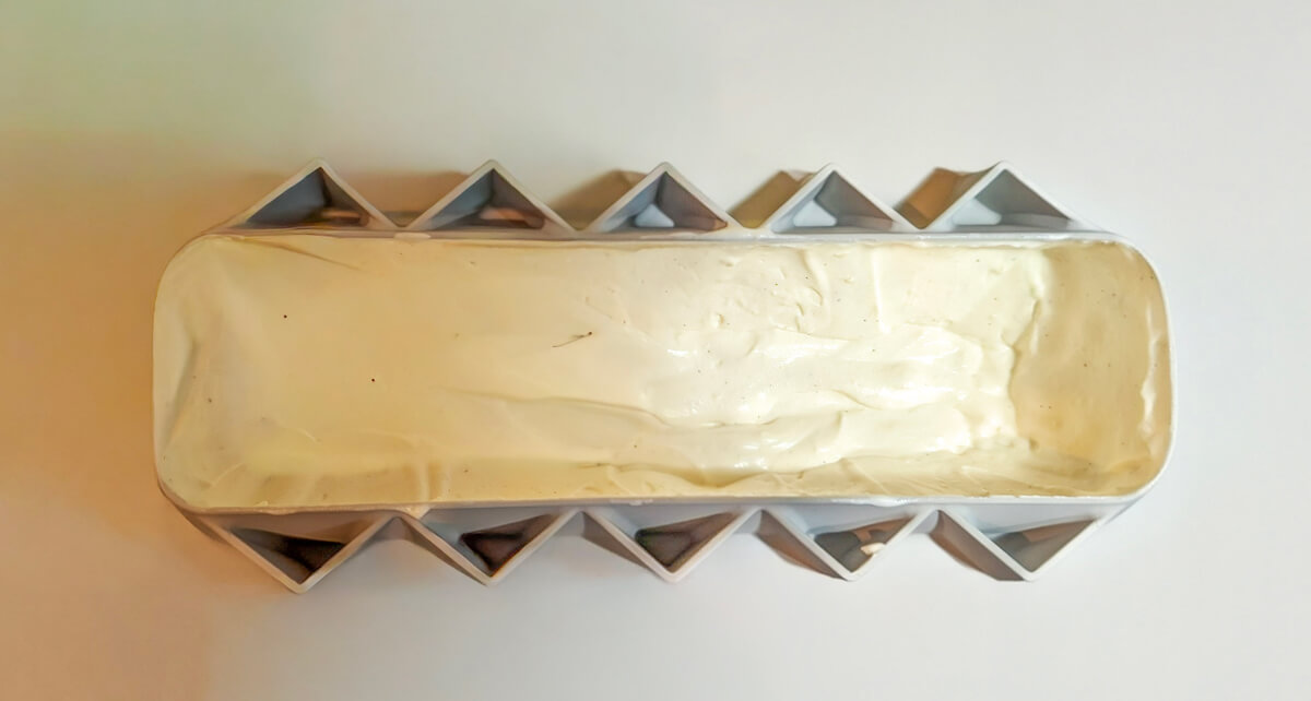 Préparation d'une mousse vanille dans un moule à bûche.