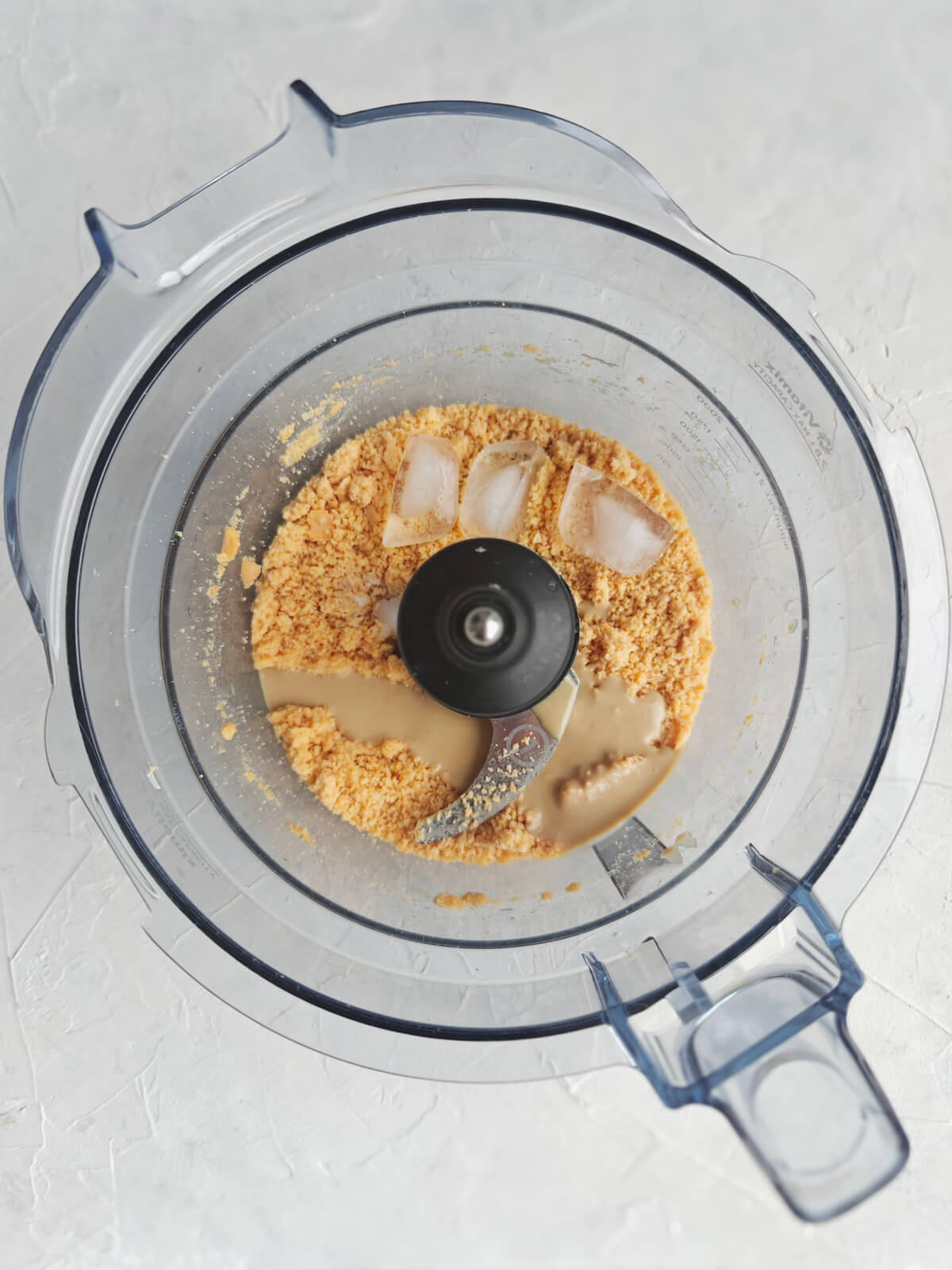 Un mélange d'ingrédients dans le bol d'un mixeur pour une recette de houmous libanais.