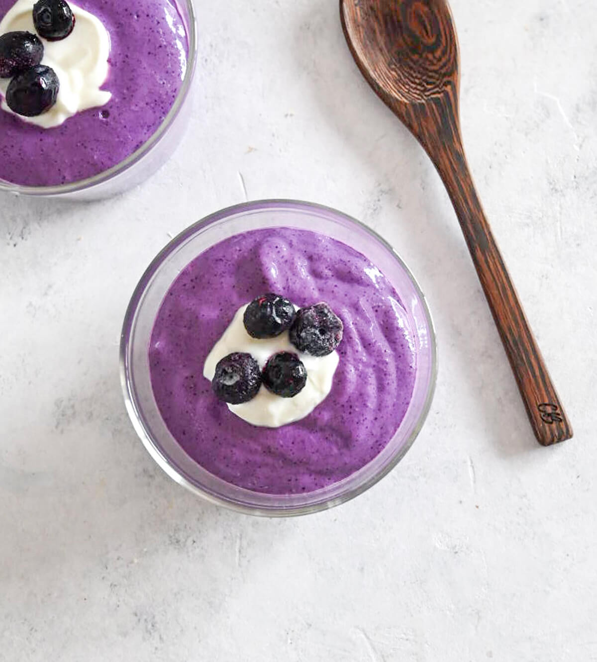 Porridge avoine-myrtilles en verrines sur fond gris clair.