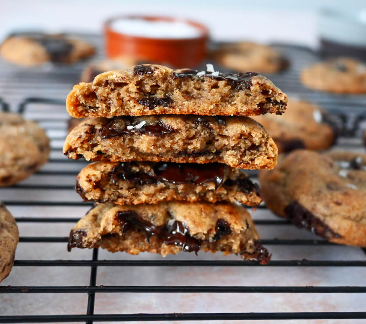 Des morceaux de cookies coupés en deux, les uns sur les autres sur une plaque de refroidissement de couleur noire.