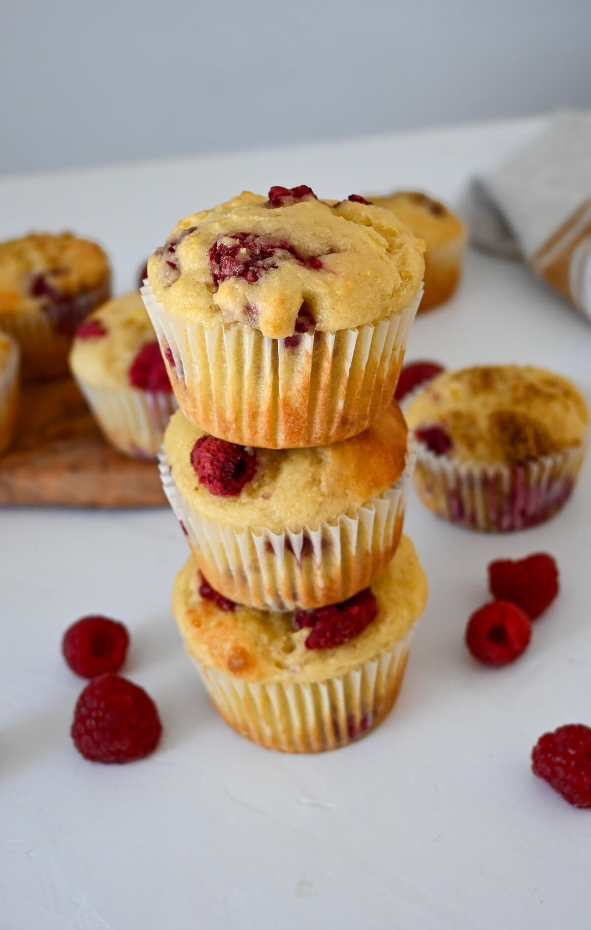 3 muffins les uns sur les autres, framboises sur le coté, sur un fond blanc.