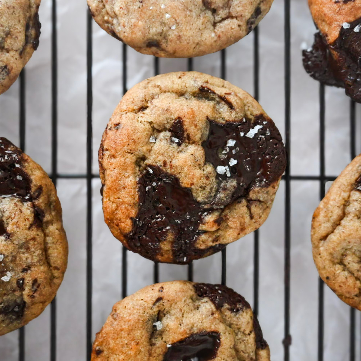 Des cookies banane chocolat sur une plaque de refroidissement noire.