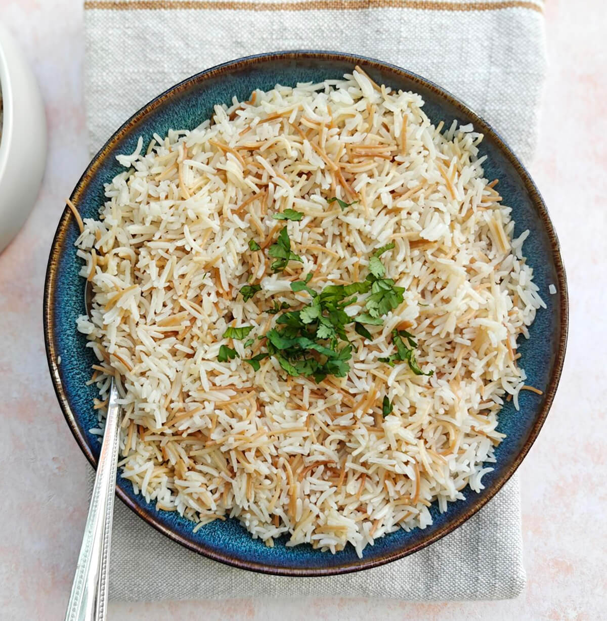 Du riz dans une assiette creuse bleue, sur un fond rose clair.