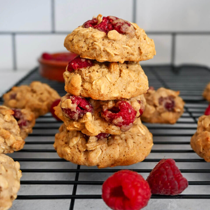 Des cookies framboise flocons d'avoine sur une plaque de refroidissement noir.