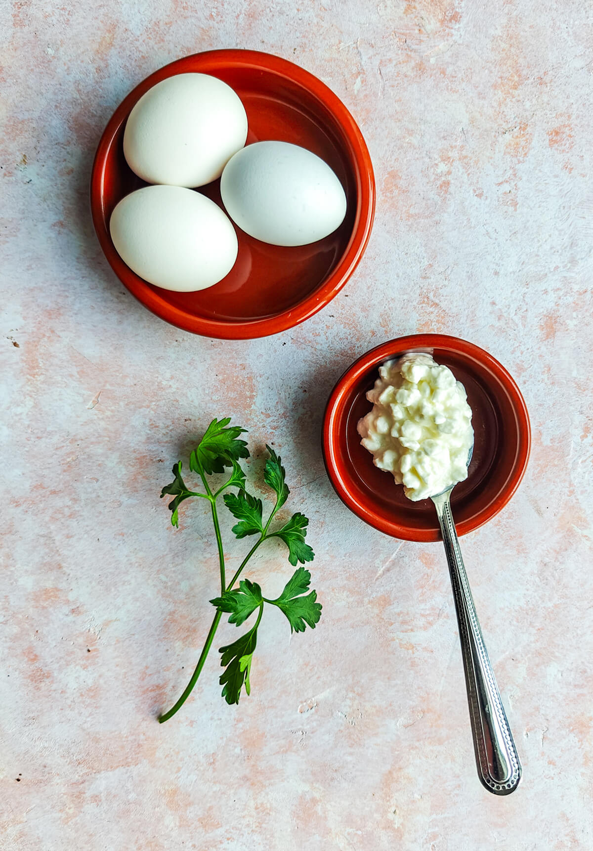 Des ingrédients pour une recette d'oeufs brouillés, sur un fond rose clair.