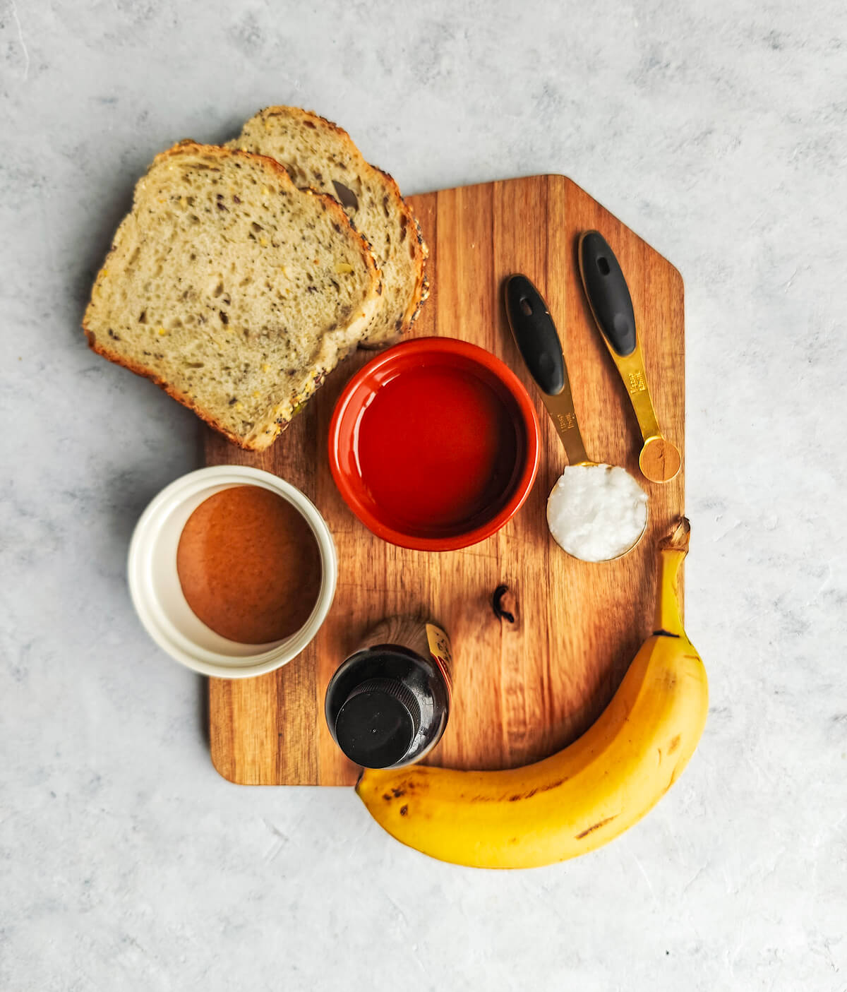 Des ingrédients pour faire une recette de tartine, sur une planche de bois, sur un fond blanc.