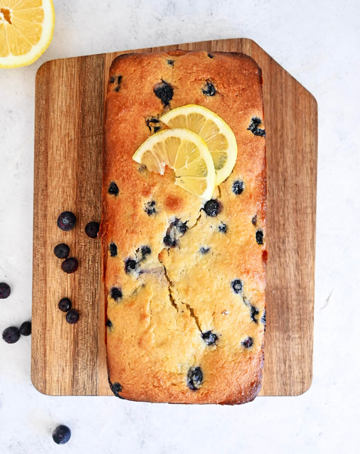 Un cake myrtilles et citron sur une planche de bois.