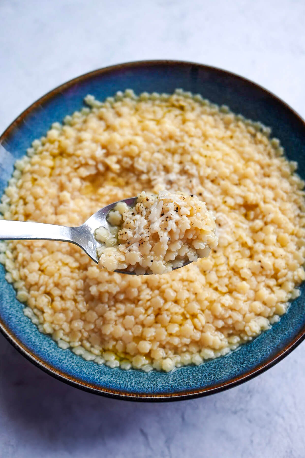 Une cuillère de pastina dans un bol bleu.