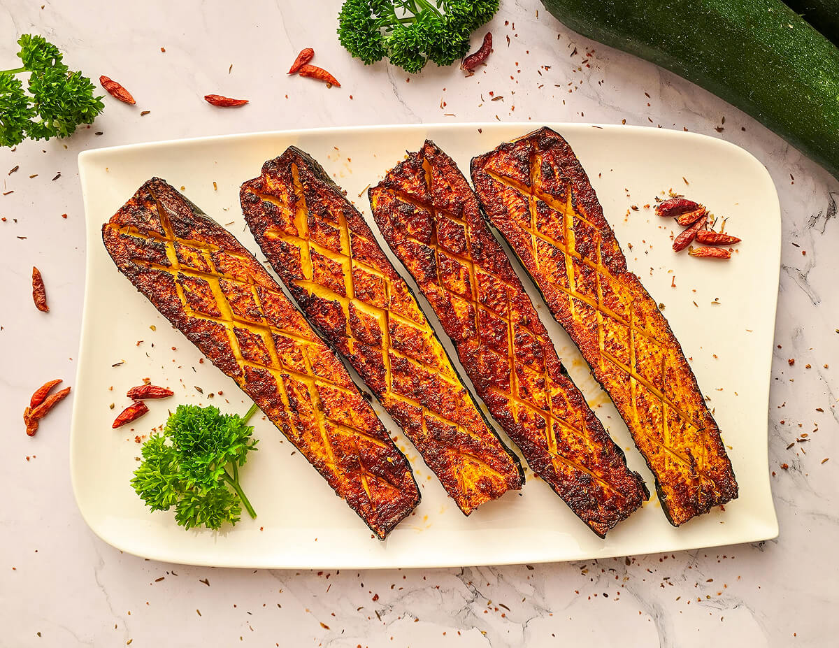 Des courgettes grillées au airfryer dans une assiette blanche.