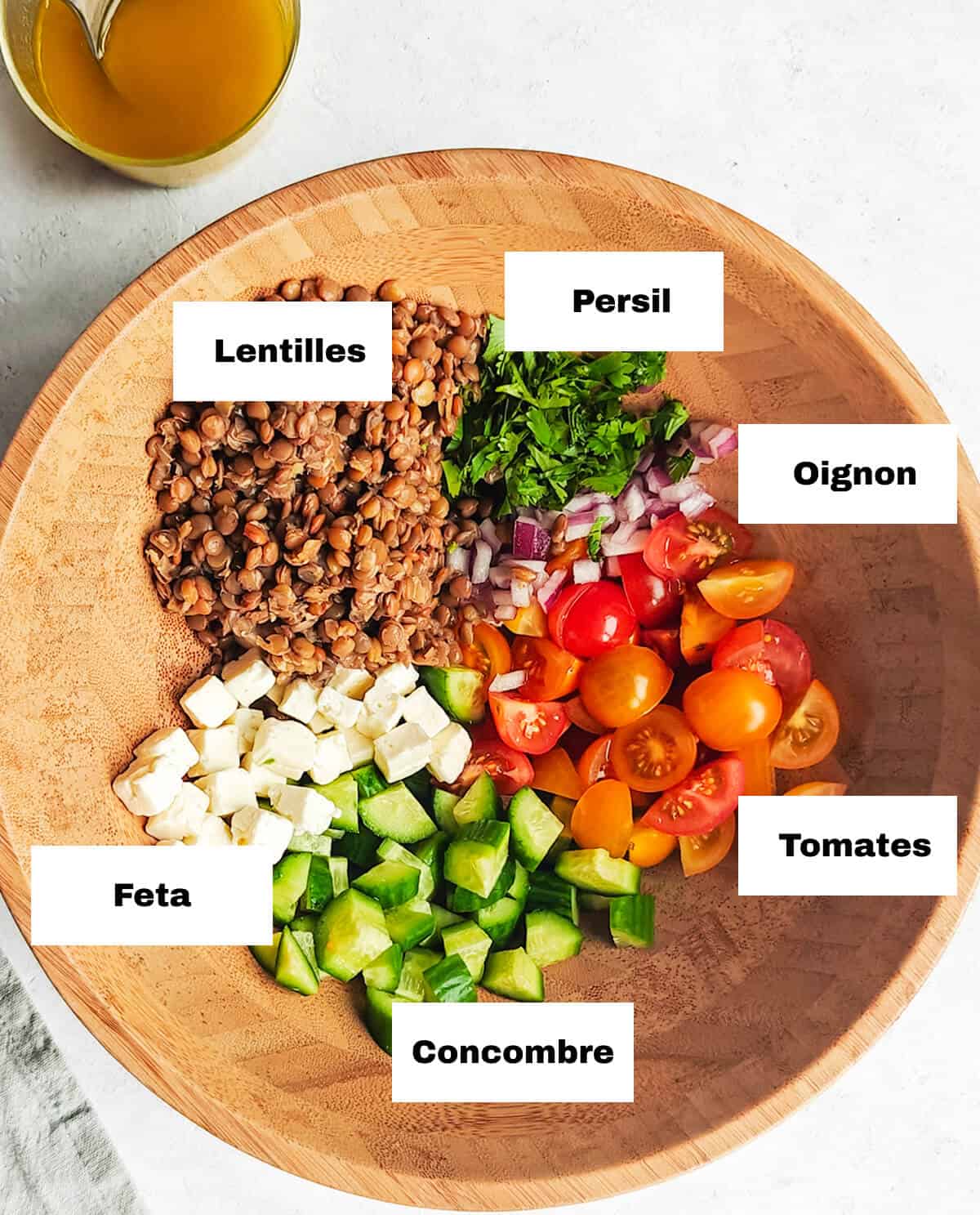 Des ingrédients pour une salade de lentilles dans un saladier en bois, vinaigrette sur le coté.