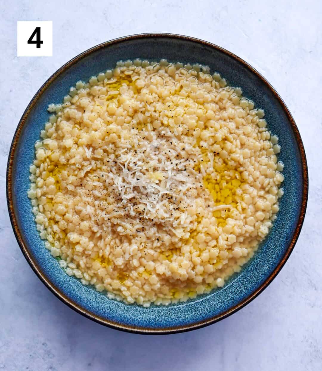 Une assiette creuse de couleur bleue, remplie de pâtes, sur un fond blanc.