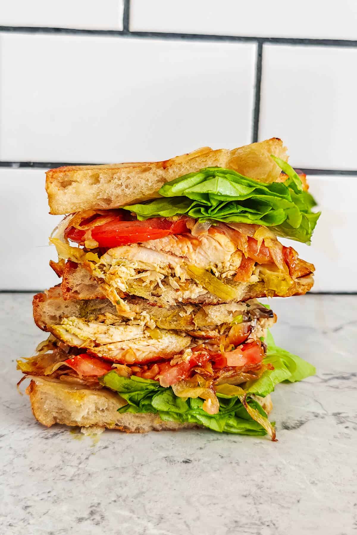 Un sandwich poulet pesto sur un fond gris clair marbré.