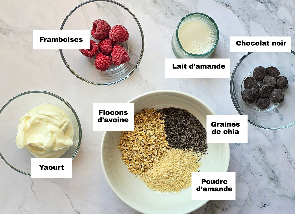 Des ingrédients pour un overnight porridge, sur un fond blanc marbré.