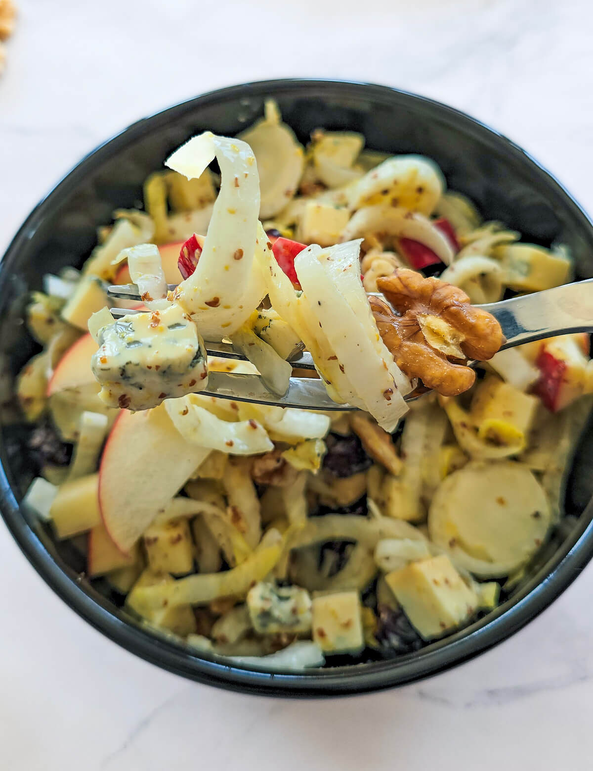 Une salade d'endives dans un bol noir.