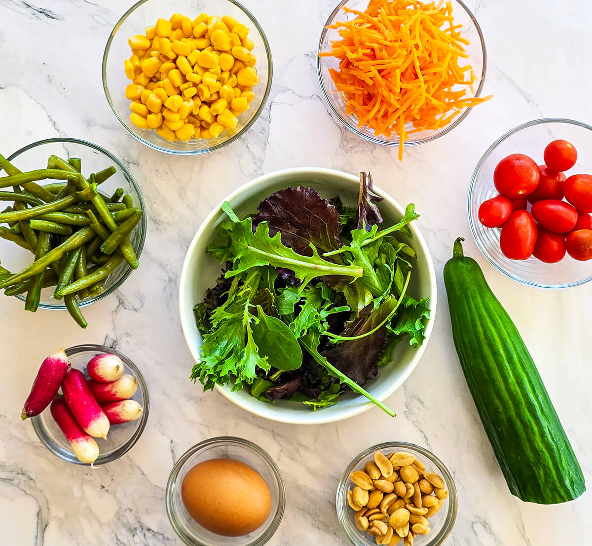 Des ingrédients pour une salade croquante sur un fond blanc marbré.