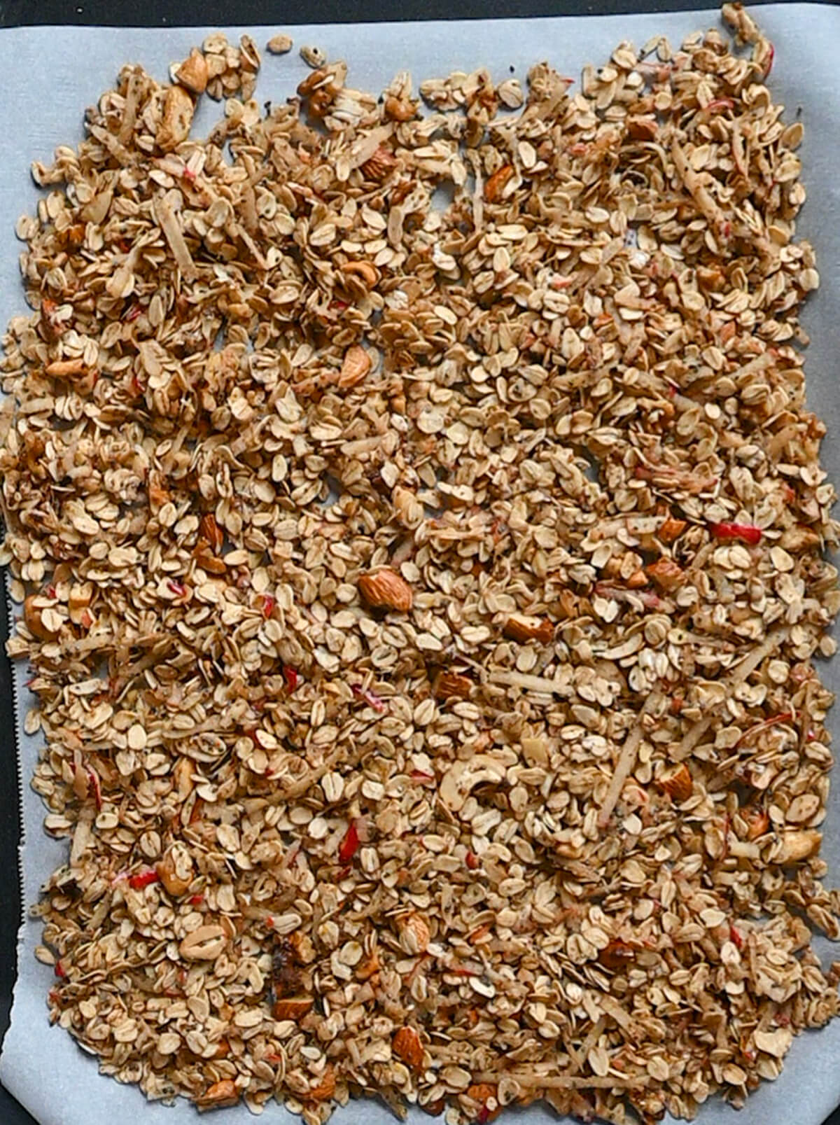 Du granola sans sucre sur une plaque de cuisson recouverte de papier sulfurisé.