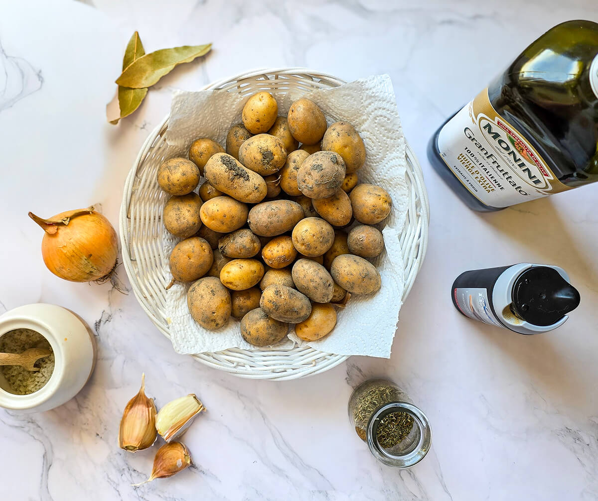 Des ingrédients pour une recette de pommes de terre grenaille, sur un fond blanc marbré.
