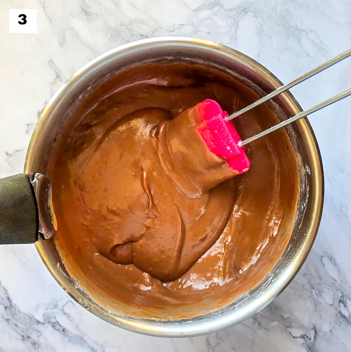 Une crème chocolat café dans une casserole avec une spatule rose.