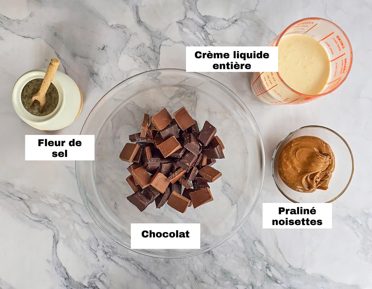 Des ingrédients pour faire une ganache au chocolat, sur un fond blanc marbré.