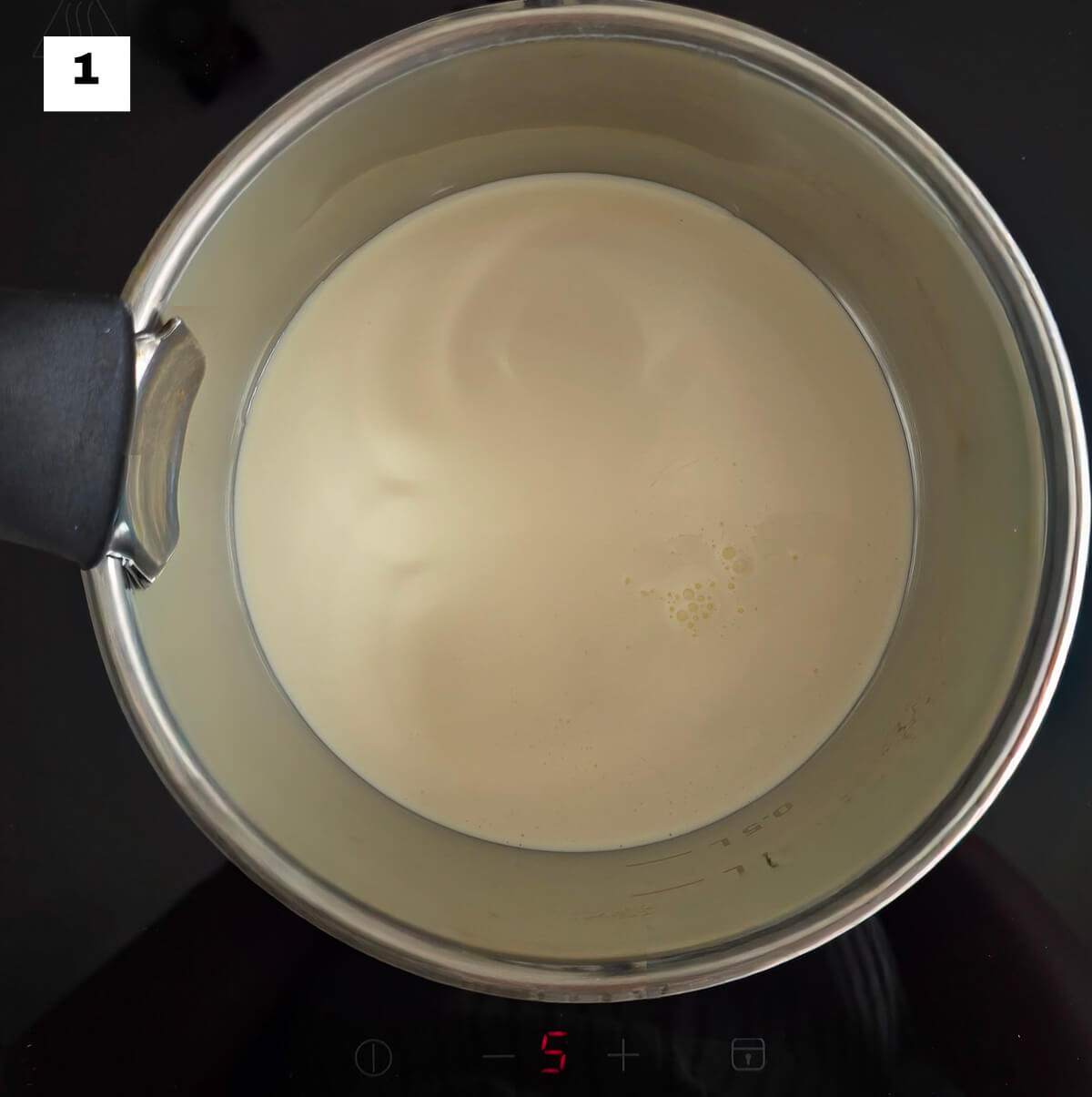De la crème liquide entière dans une casserole, sur un fond noir.