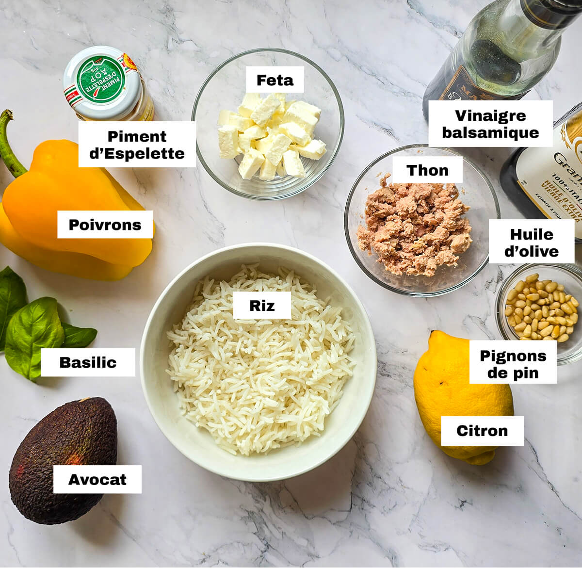 Des ingrédients pour une salade de riz au thon sur une surface blanche marbré.